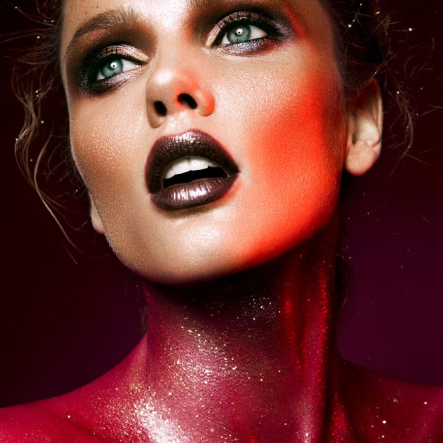 Beautiful woman with red make up and glitter on the neck and hair