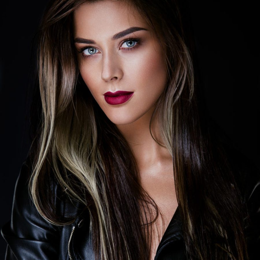 Glamour portrait of beautiful girl model with makeup and romantic wavy hairstyle. Fashion shiny highlighter on skin, sexy gloss lips make-up and dark eyebrows.